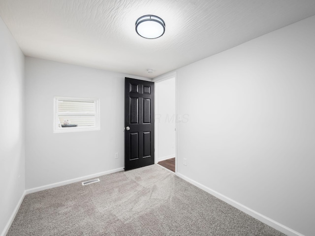 carpeted empty room featuring visible vents, baseboards, and a textured ceiling