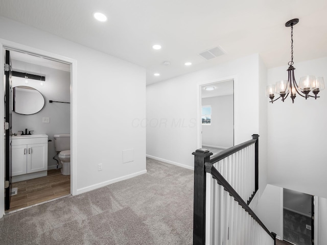 corridor featuring visible vents, a chandelier, an upstairs landing, recessed lighting, and a sink