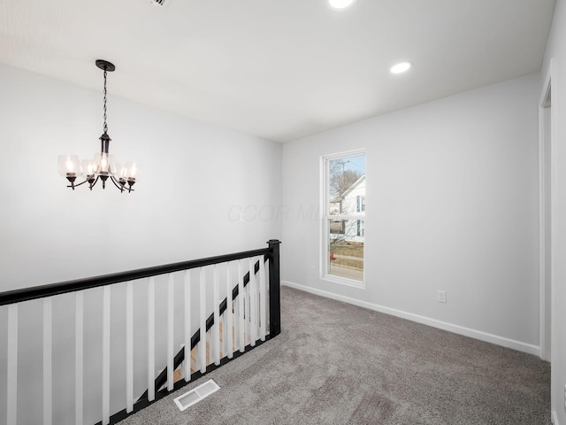 hall with carpet, visible vents, baseboards, a notable chandelier, and an upstairs landing