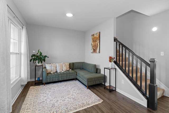 living area with baseboards, dark wood finished floors, and stairs