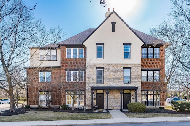 view of front of home featuring stone siding, stucco siding, a chimney, and a front yard