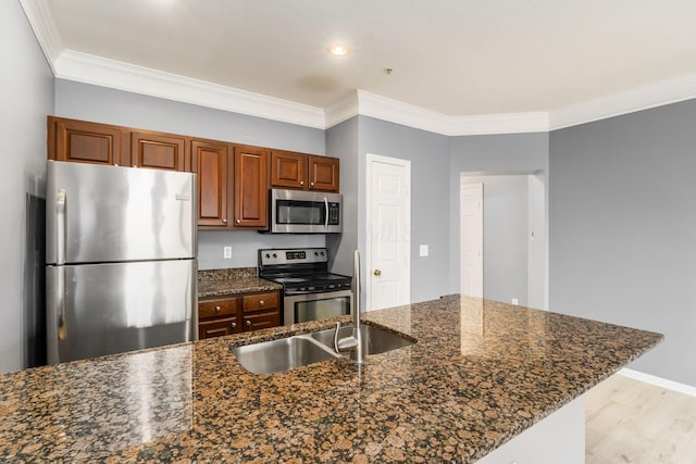 kitchen featuring a sink, stainless steel appliances, light wood-style floors, and ornamental molding