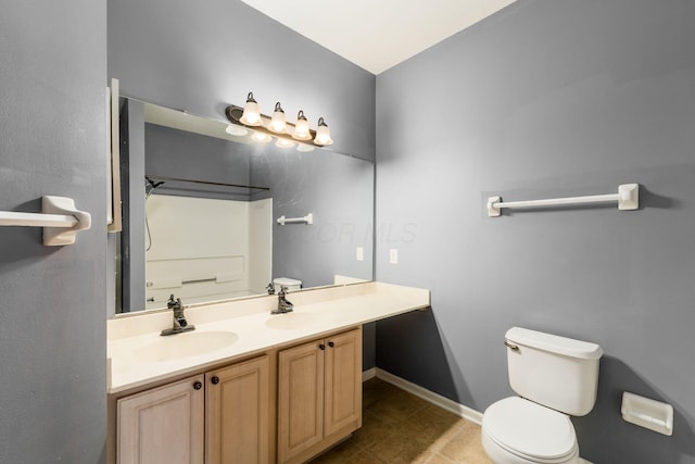 full bath featuring double vanity, toilet, baseboards, and a sink