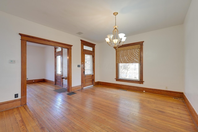 unfurnished room with visible vents, baseboards, an inviting chandelier, and light wood finished floors