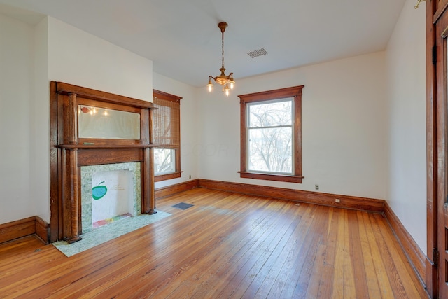 unfurnished living room featuring a chandelier, visible vents, light wood-style flooring, and baseboards