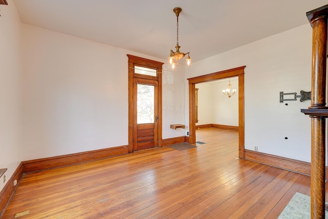 entrance foyer featuring light wood finished floors, baseboards, and an inviting chandelier