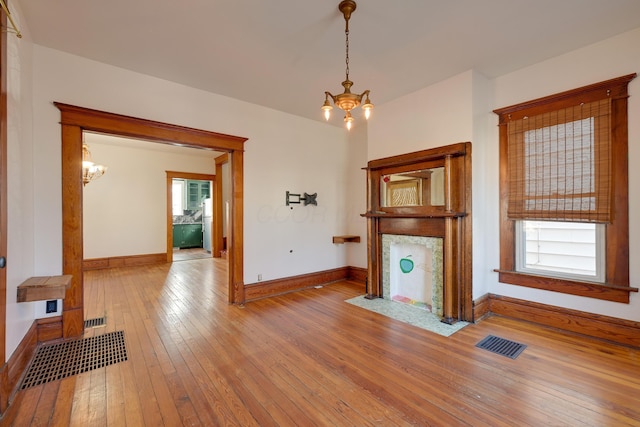 living area with baseboards, visible vents, wood-type flooring, and an inviting chandelier