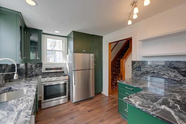 kitchen featuring a sink, backsplash, stainless steel appliances, and green cabinetry