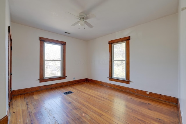 empty room with visible vents, ceiling fan, baseboards, and light wood-style floors