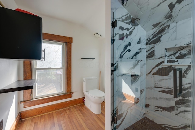 bathroom with a marble finish shower, toilet, baseboards, and wood finished floors