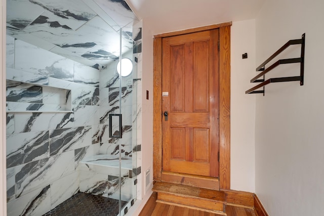 full bath with a marble finish shower and wood finished floors