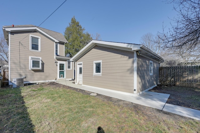 rear view of property with central air condition unit, a lawn, and fence