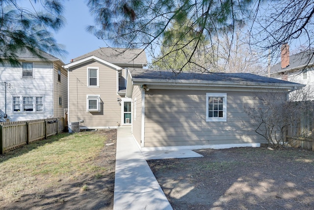 back of property featuring central air condition unit, a lawn, and fence