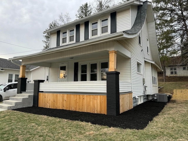 view of front of house with covered porch, a front lawn, and central AC