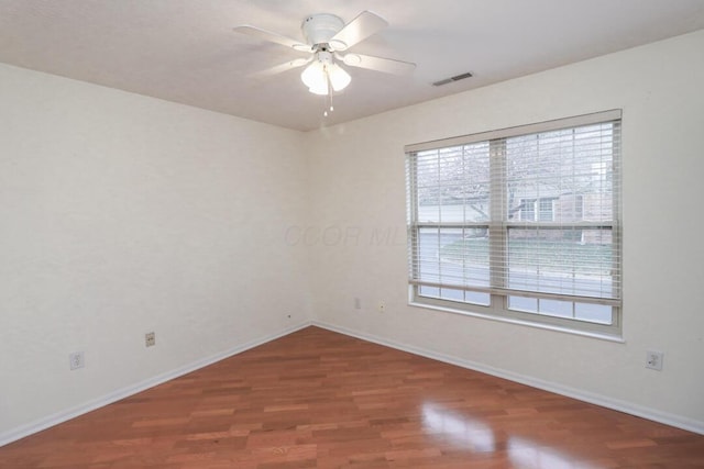 spare room featuring visible vents, baseboards, ceiling fan, and wood finished floors
