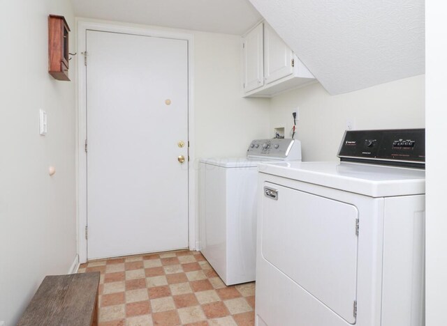 clothes washing area with light floors, cabinet space, and washer and dryer