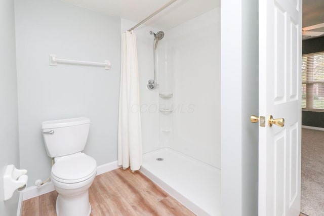 bathroom with wood finished floors, baseboards, curtained shower, and toilet