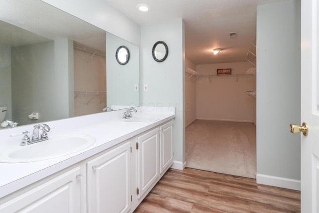 full bathroom with double vanity, a sink, and baseboards