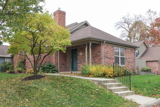 view of front of house with a shingled roof, a chimney, a front lawn, and brick siding