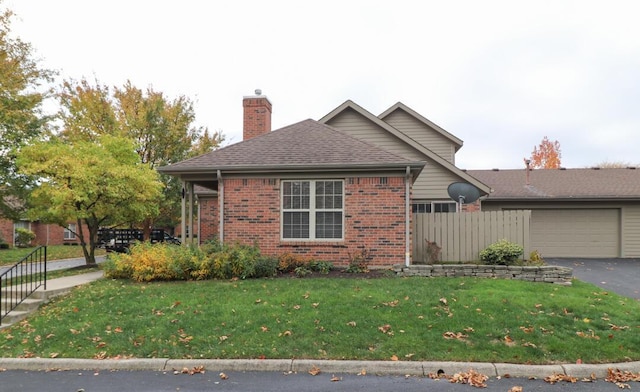 view of front facade with a garage, a front yard, a chimney, brick siding, and driveway