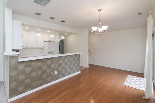kitchen with an inviting chandelier, white refrigerator with ice dispenser, baseboards, wood finished floors, and visible vents