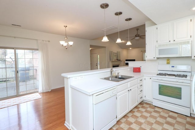 kitchen featuring visible vents, a sink, light countertops, a peninsula, and white appliances
