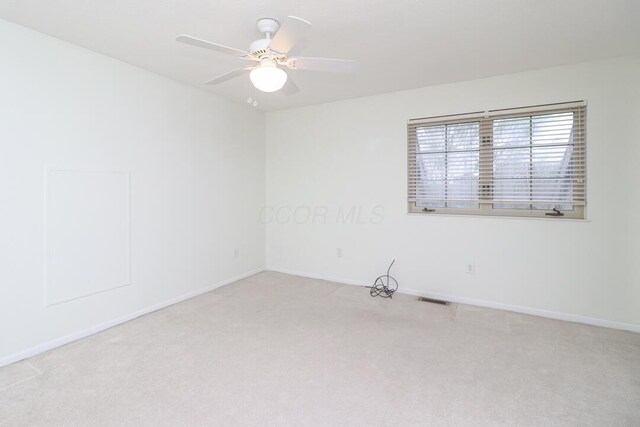 carpeted empty room featuring baseboards, a ceiling fan, and visible vents