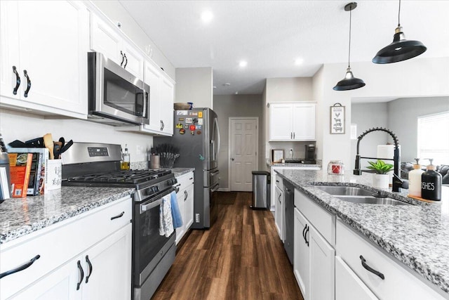 kitchen featuring a sink, white cabinetry, stainless steel appliances, light stone countertops, and hanging light fixtures