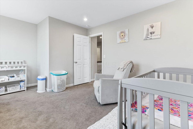 bedroom featuring a nursery area, baseboards, and carpet