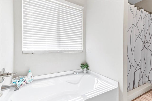 bathroom with curtained shower and a bath