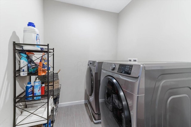 clothes washing area with laundry area, baseboards, and washing machine and clothes dryer