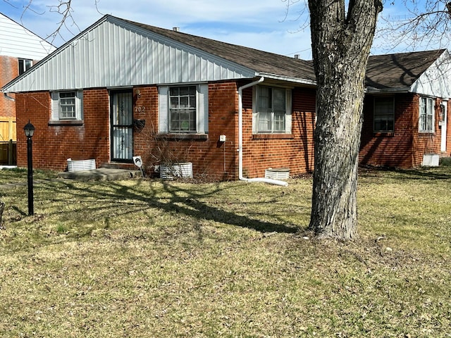 view of front facade featuring board and batten siding, a front lawn, and brick siding