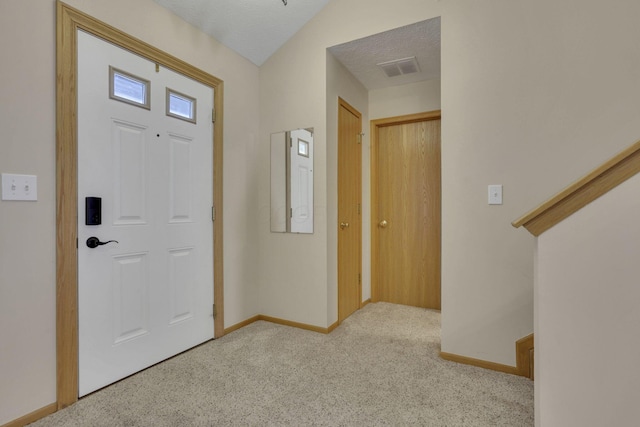 carpeted entrance foyer featuring visible vents, baseboards, and a textured ceiling