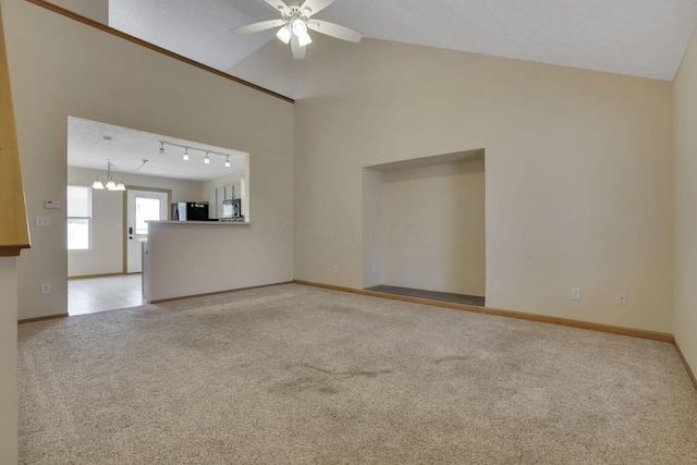 unfurnished living room with carpet flooring, ceiling fan with notable chandelier, track lighting, and baseboards