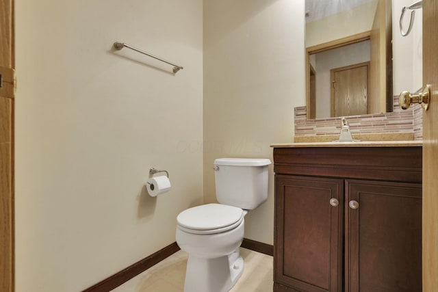 half bathroom featuring baseboards, backsplash, vanity, and toilet