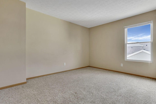 carpeted spare room featuring baseboards and a textured ceiling