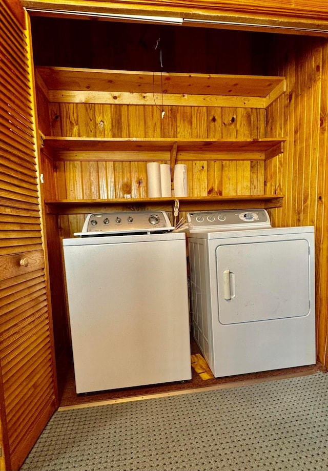 washroom with laundry area, wood walls, and separate washer and dryer