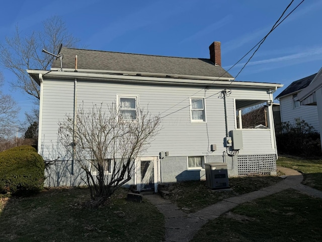 back of property with a chimney and roof with shingles