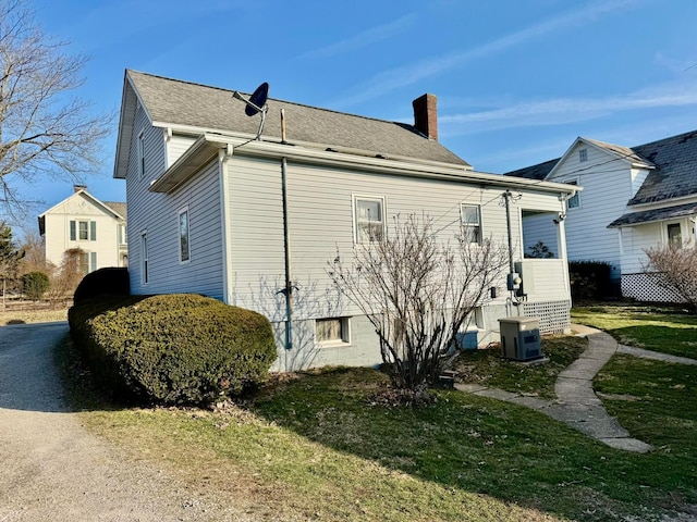 view of property exterior with central air condition unit, a chimney, and a yard