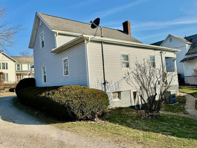 view of side of home with ac unit and a chimney