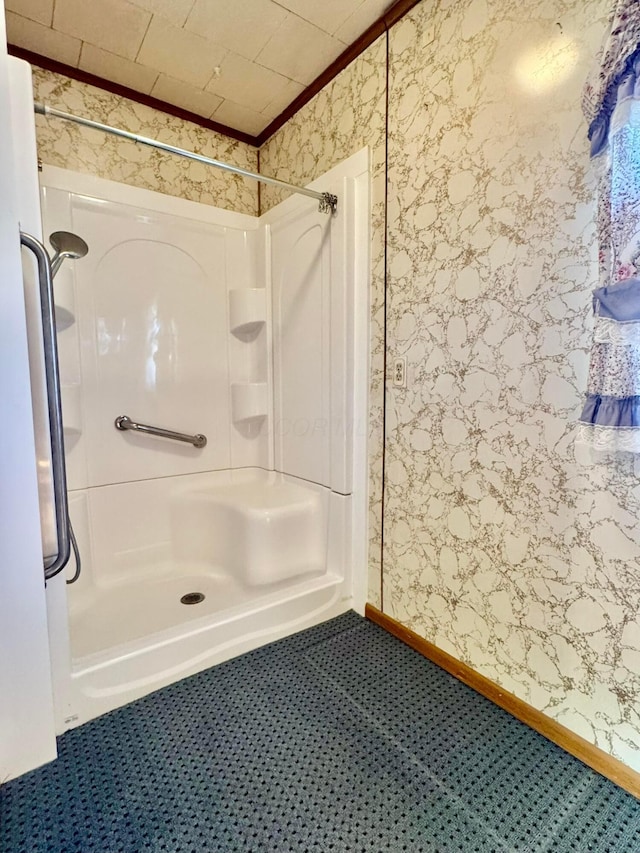 bathroom featuring baseboards, a stall shower, and wallpapered walls