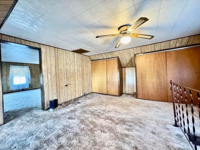 bonus room with carpet, ceiling fan, and wooden walls