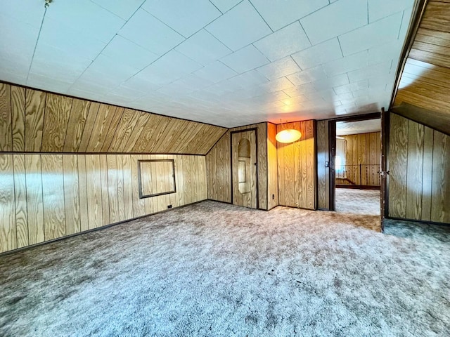 additional living space with wooden walls, carpet, and vaulted ceiling