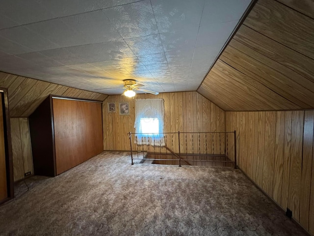 bonus room featuring lofted ceiling, carpet, wood walls, and a ceiling fan