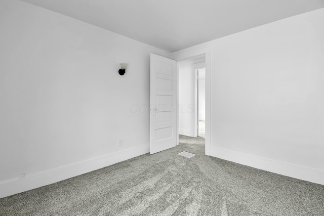 empty room featuring carpet and baseboards