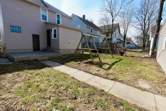 rear view of house featuring a patio area, a lawn, entry steps, and fence