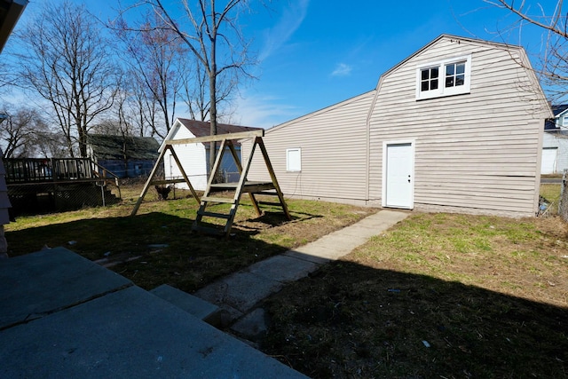 back of house with a deck, a gambrel roof, and a yard