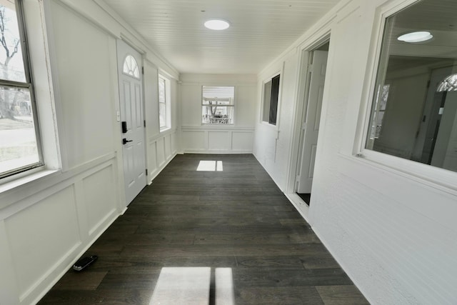 hall with dark wood-type flooring and a decorative wall