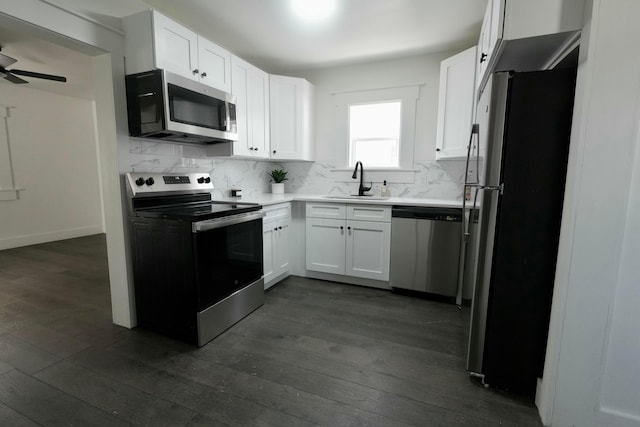 kitchen with dark wood-style floors, a sink, appliances with stainless steel finishes, white cabinetry, and backsplash