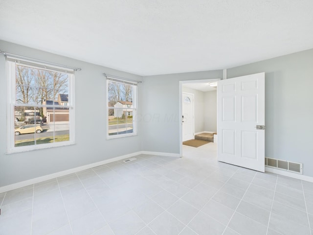 unfurnished room with light tile patterned floors, baseboards, and visible vents